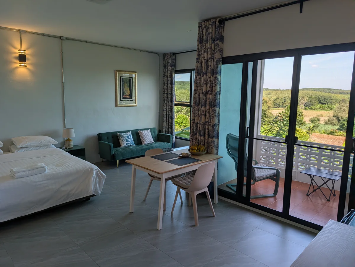 Baan Lillawadee interior with bed, sitting area and doors opening onto its balcony.